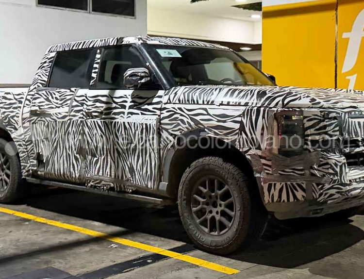 Vista lateral y frontal de tres cuartos de la nueva pick-up Nissan Frontier Pro híbrida enchufable cubierta con camuflaje de cebra, estacionada en un parqueadero en Bucaramanga durante sus pruebas de ruta.