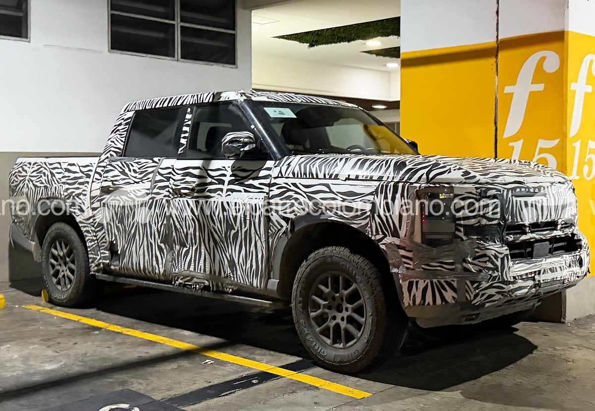 Vista lateral y frontal de tres cuartos de la nueva pick-up Nissan Frontier Pro híbrida enchufable cubierta con camuflaje de cebra, estacionada en un parqueadero en Bucaramanga durante sus pruebas de ruta.