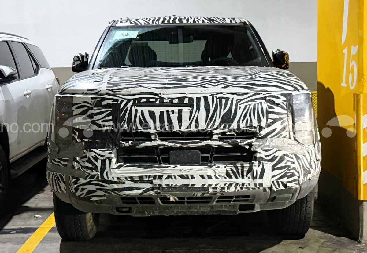 Vista frontal directa de la Nissan Frontier Pro híbrida camuflada, destacando su parrilla cuadrada y el diseño oculto de sus luces diurnas LED en forma de