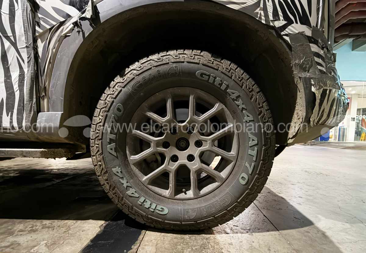 Primer plano de la rueda trasera de la Nissan Frontier Pro PHEV, mostrando el rin de aleación oscurecido y la llanta todoterreno Giti 4x4 AT70.