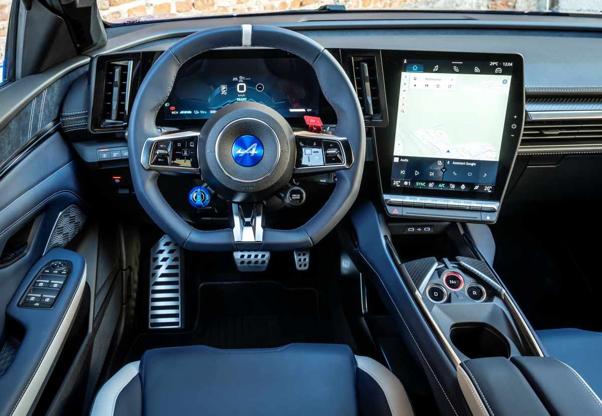 Puesto de conducción del Alpine A390 GTS, detallando el volante achatado deportivo con botones satelitales, el cuadro de instrumentos digital y la gran pantalla táctil vertical central.