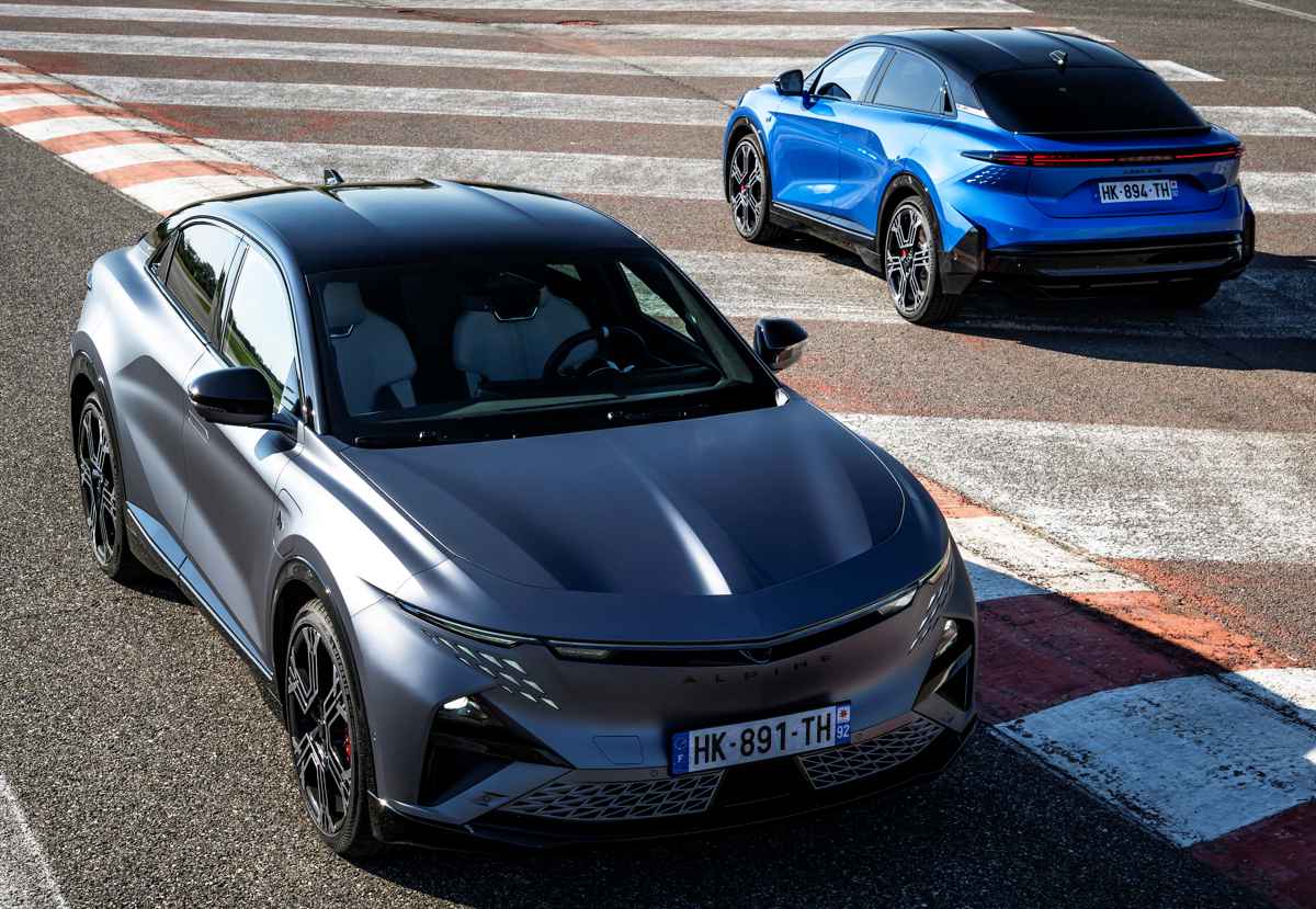 Dos vehículos Alpine A390 GTS en una pista de carreras; uno en color gris mate en primer plano y otro azul al fondo, preparados para pruebas de alto rendimiento.