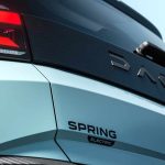 Detalle de la compuerta trasera del nuevo Dacia Spring eléctrico en color azul claro, mostrando el faro LED, la franja negra texturizada con la inscripción Dacia y el emblema Spring Electric.