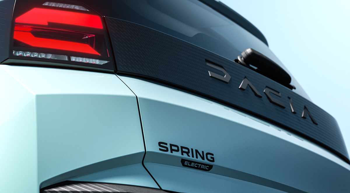 Detalle de la compuerta trasera del nuevo Dacia Spring eléctrico en color azul claro, mostrando el faro LED, la franja negra texturizada con la inscripción Dacia y el emblema Spring Electric.