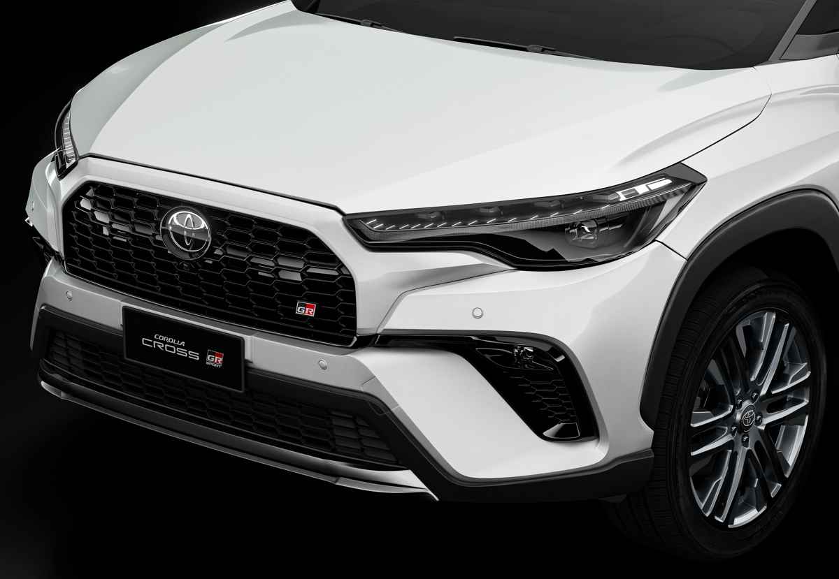 Primer plano de la parte frontal del Toyota Corolla Cross GR Sport, detallando la parrilla trapezoidal dividida, las luces LED diurnas y el emblema de Gazoo Racing.