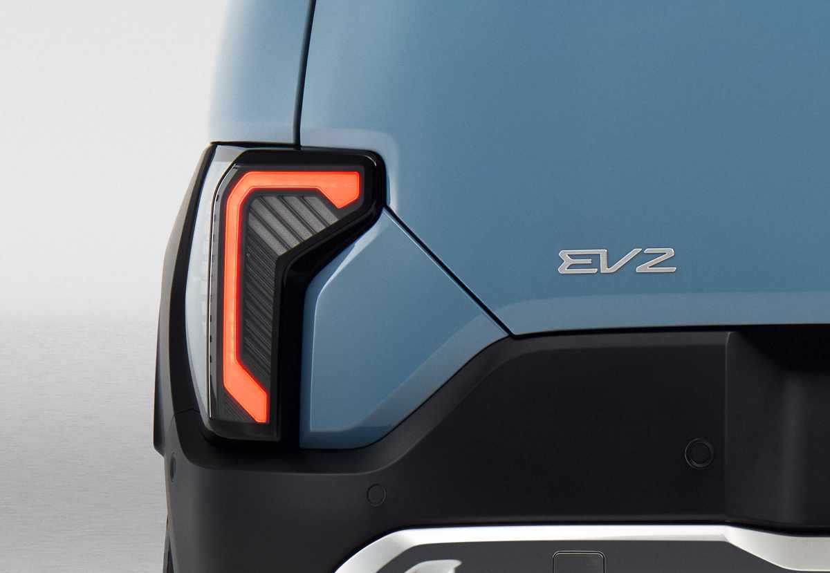 Acercamiento a la peculiar luz trasera LED del Kia EV2, ubicada en una posición baja cerca al bumper y rodeada por una moldura oscura.