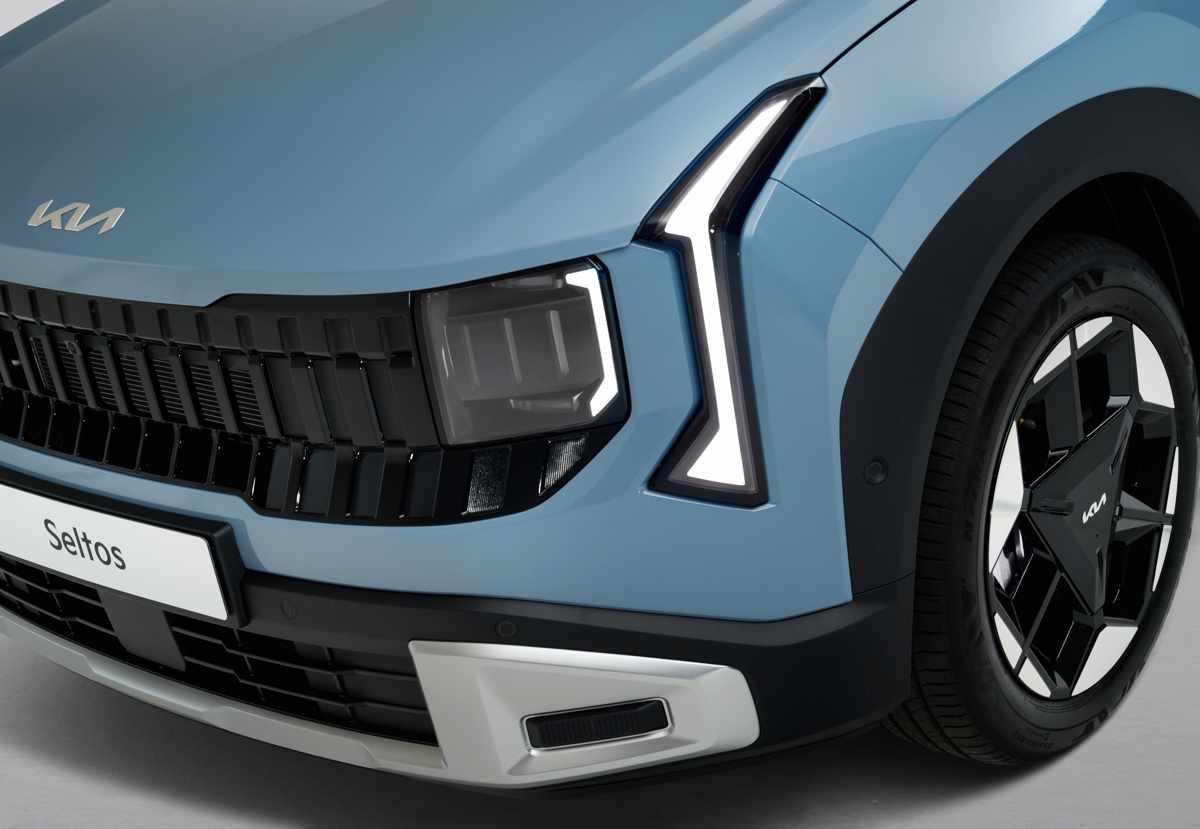 Primer plano del imponente faro frontal de la nueva Kia Seltos, detallando la luz diurna LED en forma trapezoidal y las luces principales oscurecidas.