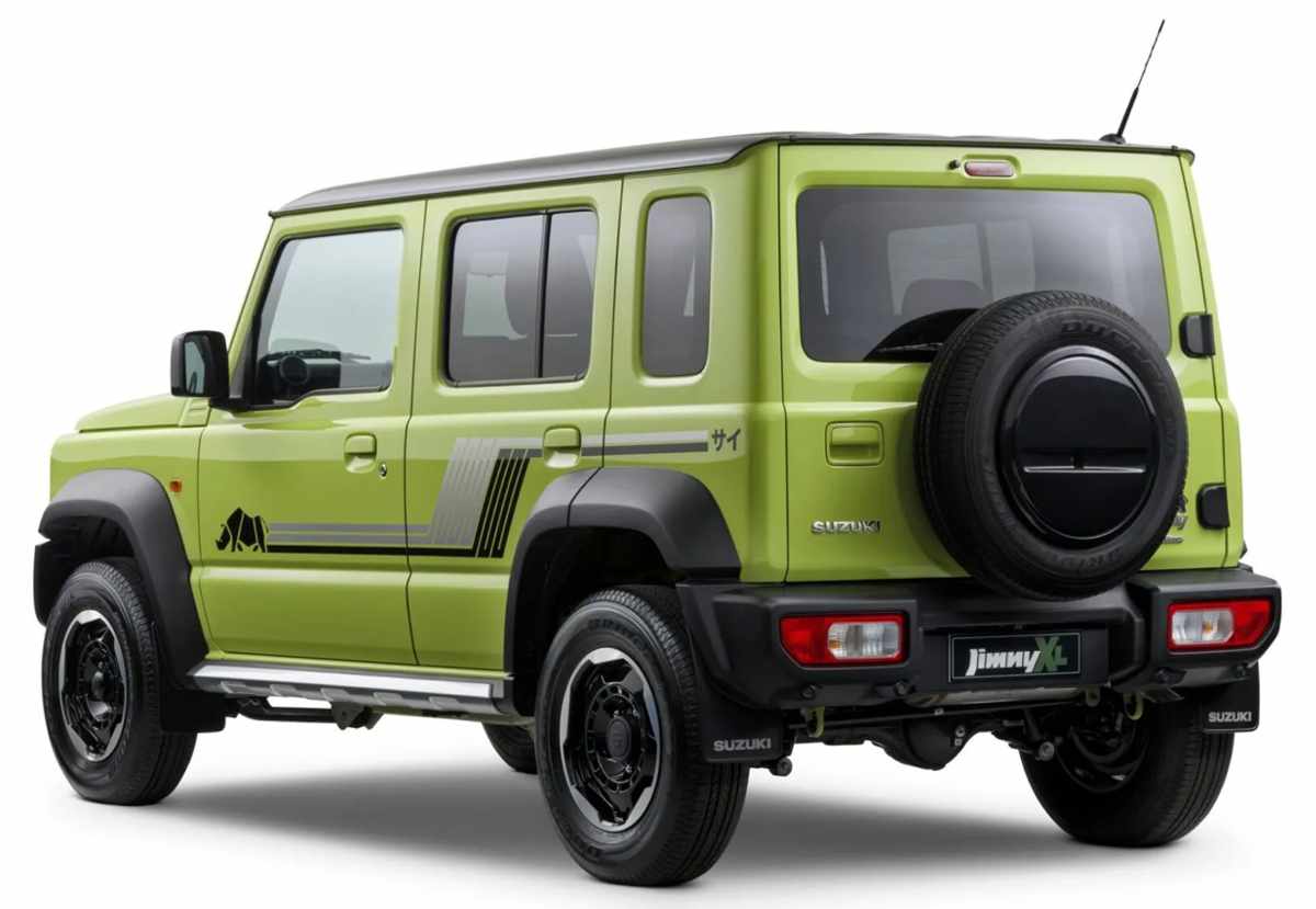 Perspectiva trasera de tres cuartos del Suzuki Jimny XL Rhino, detallando la llanta de repuesto montada en el portón, los guardabarros plásticos y los faldones plateados.