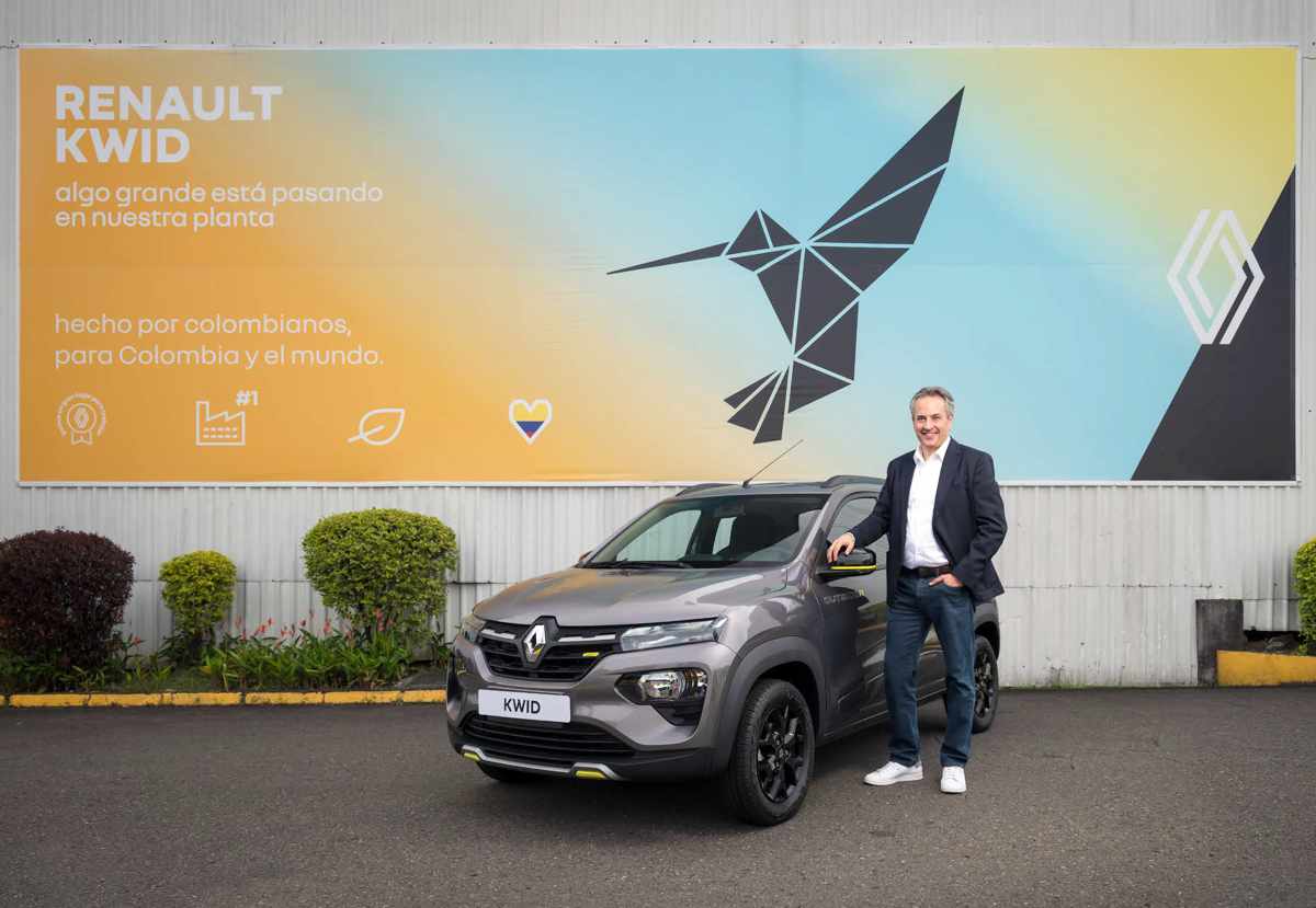 Juan Camilo Vélez, presidente de Renault-Sofasa, posando sonriente junto a un Renault Kwid gris frente a un mural con un colibrí geométrico que celebra la producción nacional.