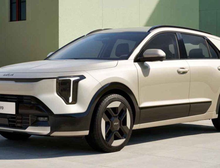 Vista frontal tres cuartos de la nueva SUV híbrida Kia Niro 2027 color beige estacionada frente a un edificio moderno a la luz del día, destacando sus nuevas luces diurnas LED en forma de T y rines aerodinámicos.