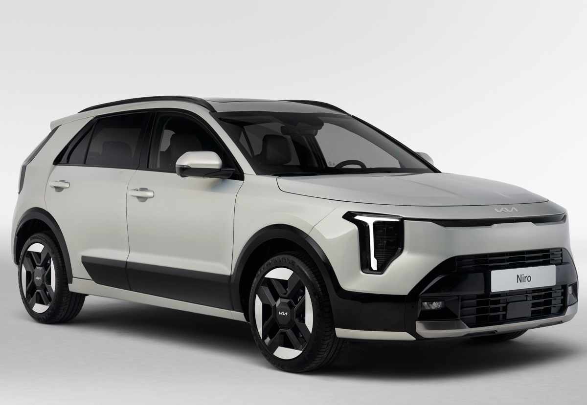 Fotografía de estudio en vista tres cuartos frontal de la Kia Niro híbrida 2027 color beige sobre fondo blanco, resaltando la caída del capó, el rediseño del bumper delantero y las gruesas molduras negras inferiores.