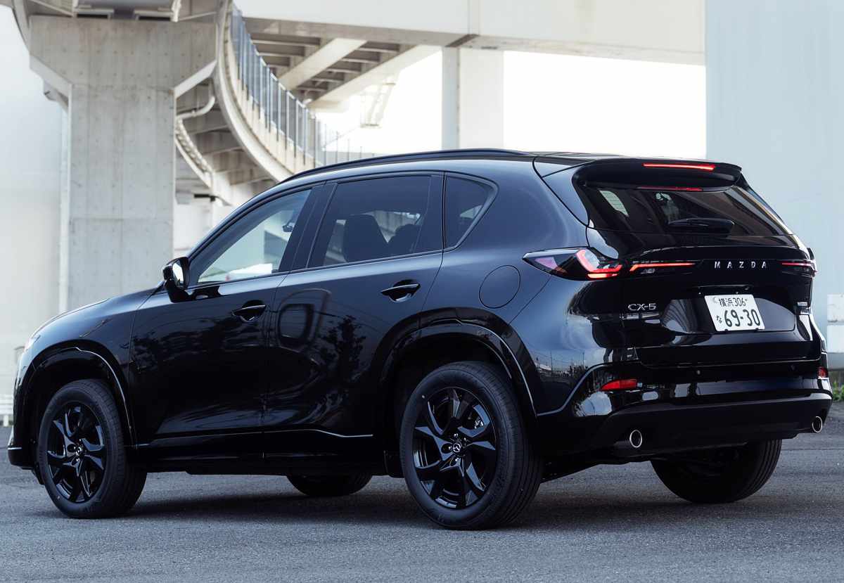 Vista tres cuartos trasera de la Mazda CX-5 de tercera generación en color negro, exhibiendo sus nuevas luces ópticas traseras LED más delgadas, spoiler superior de techo y doble salida de escape cromada.