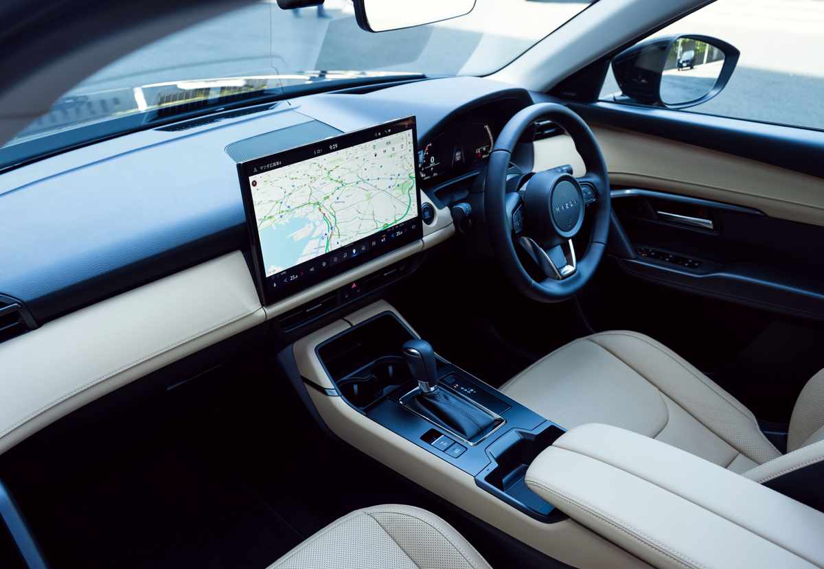 Interior del habitáculo de la nueva Mazda CX-5, detallando el tablero con la gran pantalla multimedia de 15,6 pulgadas que muestra un mapa de navegación, consola central con palanca de cambios y tapicería premium de cuero color beige Sports Tan.