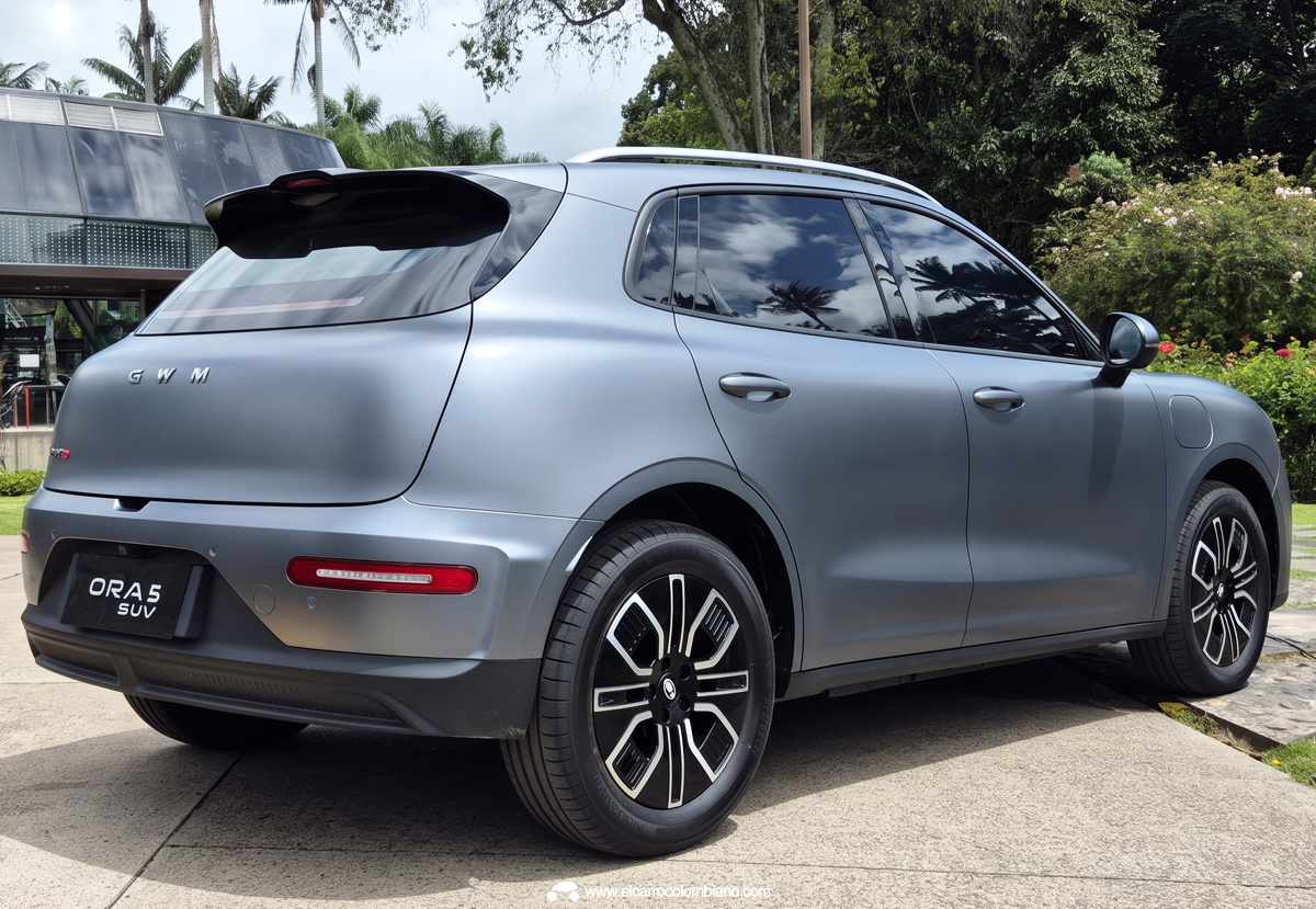 Perfil lateral y zona posterior de la camioneta GWM Ora 5 en color gris mate, exhibiendo la pronunciada caída del techo tipo coupé, el alerón superior y las luces intermitentes reubicadas en el bumper inferior.