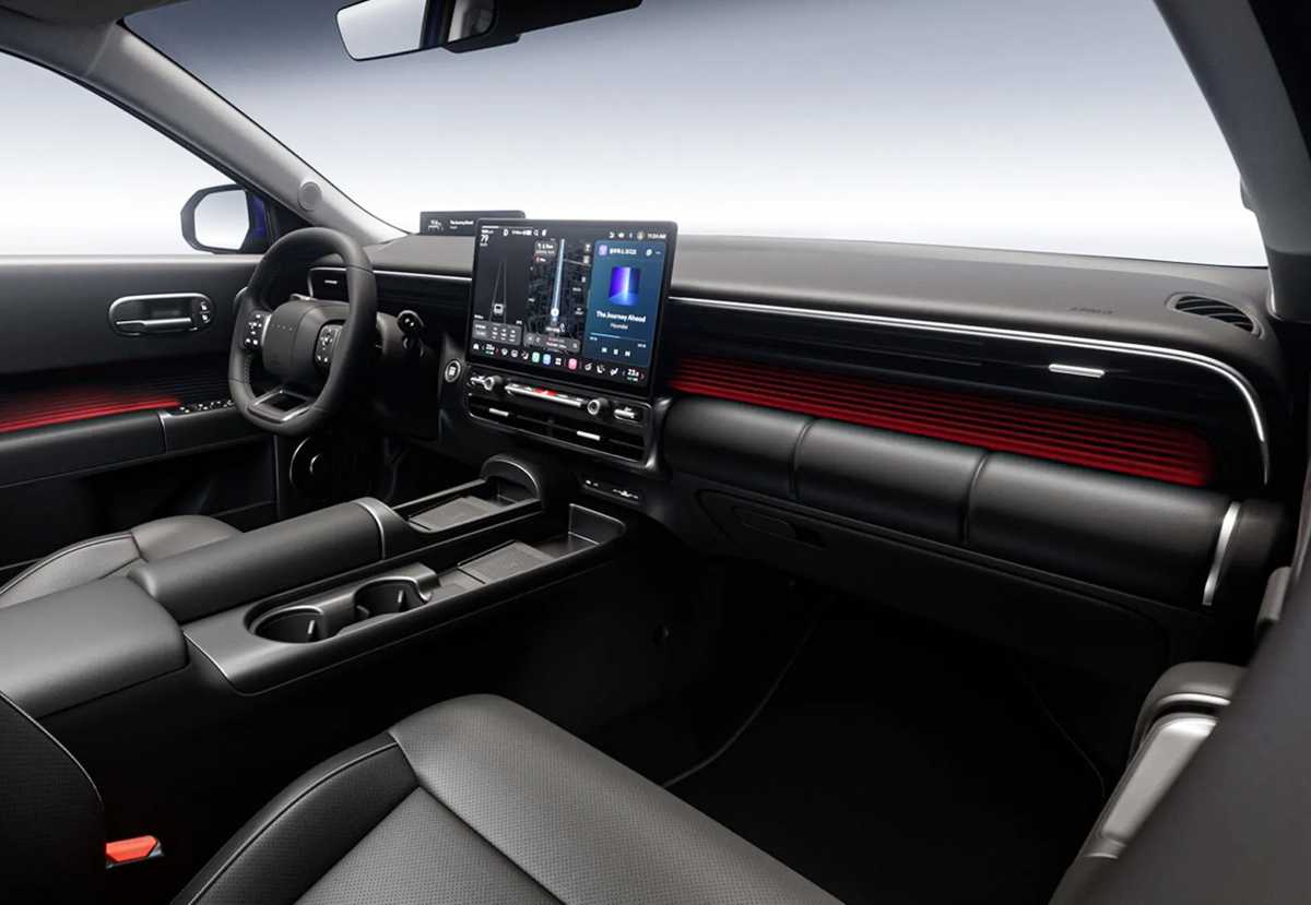 Habitáculo interior moderno del nuevo Hyundai Elantra 2027, mostrando un tablero envolvente de formas redondeadas con dos pantallas digitales continuas, iluminación ambiental roja, volante de tres radios y una consola central minimalista.
