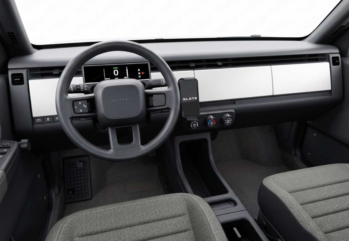 Interior minimalista de la Slate Truck, destacando un pequeño tablero digital tras el volante, un soporte para celular y asientos de tela, eliminando la pantalla central tradicional.
