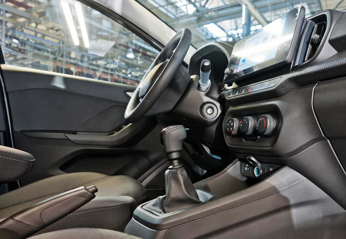 Primer plano de la consola central de la Lada Iskra SW Drive, enfocando la palanca de la nueva caja manual de 6 velocidades y los mandos del aire acondicionado.