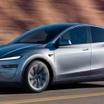 Tesla Model Y plateado en movimiento por una carretera despejada con montañas de fondo, representando el carro más vendido de Colombia en mayo.