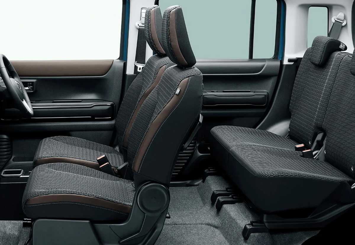 Habitáculo interior del Mazda Flair Crossover con asientos tapizados en tela y bordes marrones, demostrando la amplitud y versatilidad de sus plazas traseras.