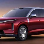 Vista de tres cuartos frontal del nuevo SUV eléctrico premium BYD Great Tang color rojo oscuro brillante, estacionado en un entorno desértico al atardecer, resaltando su gran tamaño y líneas de diseño futurista.