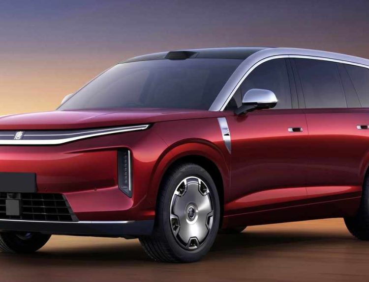 Vista de tres cuartos frontal del nuevo SUV eléctrico premium BYD Great Tang color rojo oscuro brillante, estacionado en un entorno desértico al atardecer, resaltando su gran tamaño y líneas de diseño futurista.