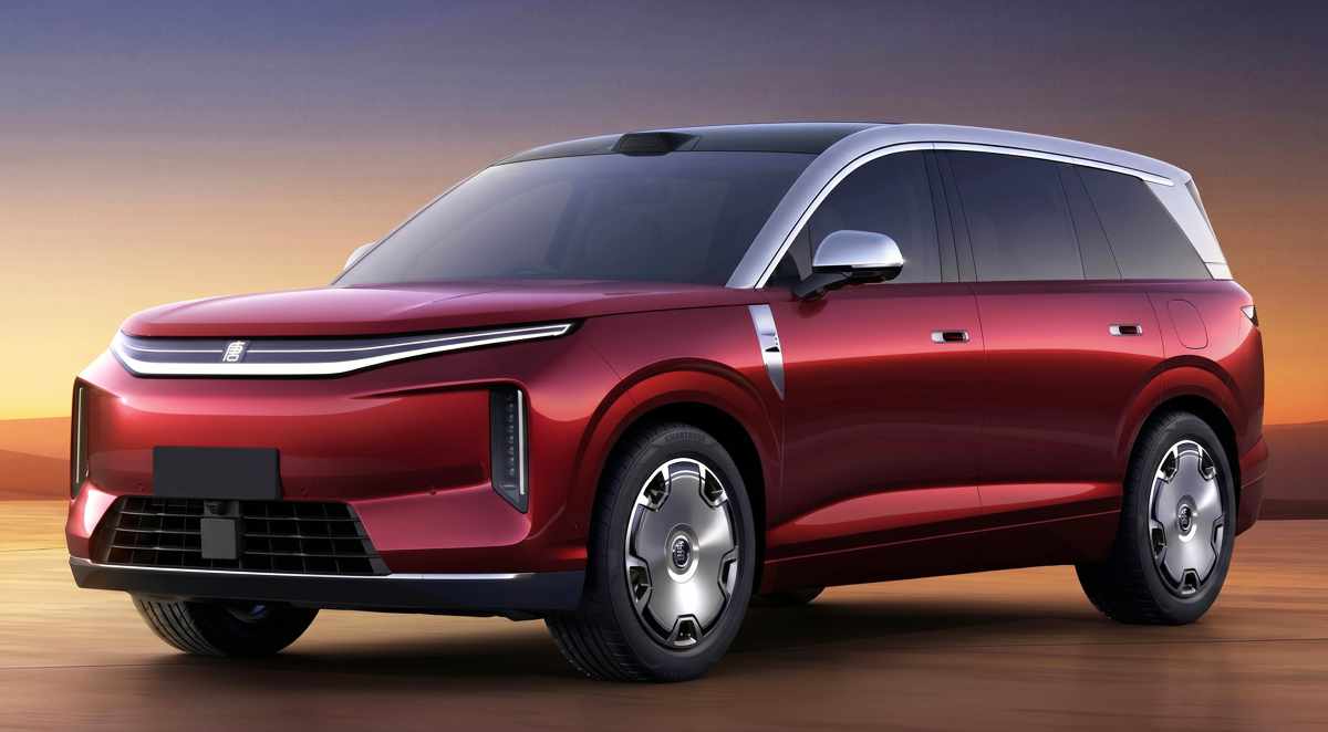 Vista de tres cuartos frontal del nuevo SUV eléctrico premium BYD Great Tang color rojo oscuro brillante, estacionado en un entorno desértico al atardecer, resaltando su gran tamaño y líneas de diseño futurista.