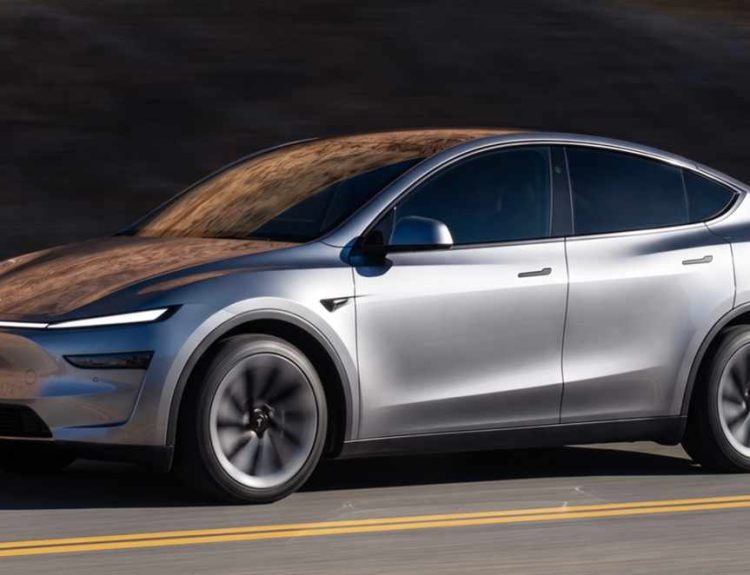 Crossover eléctrico Tesla Model Y color plata en movimiento sobre una carretera con líneas amarillas durante el día en Colombia.