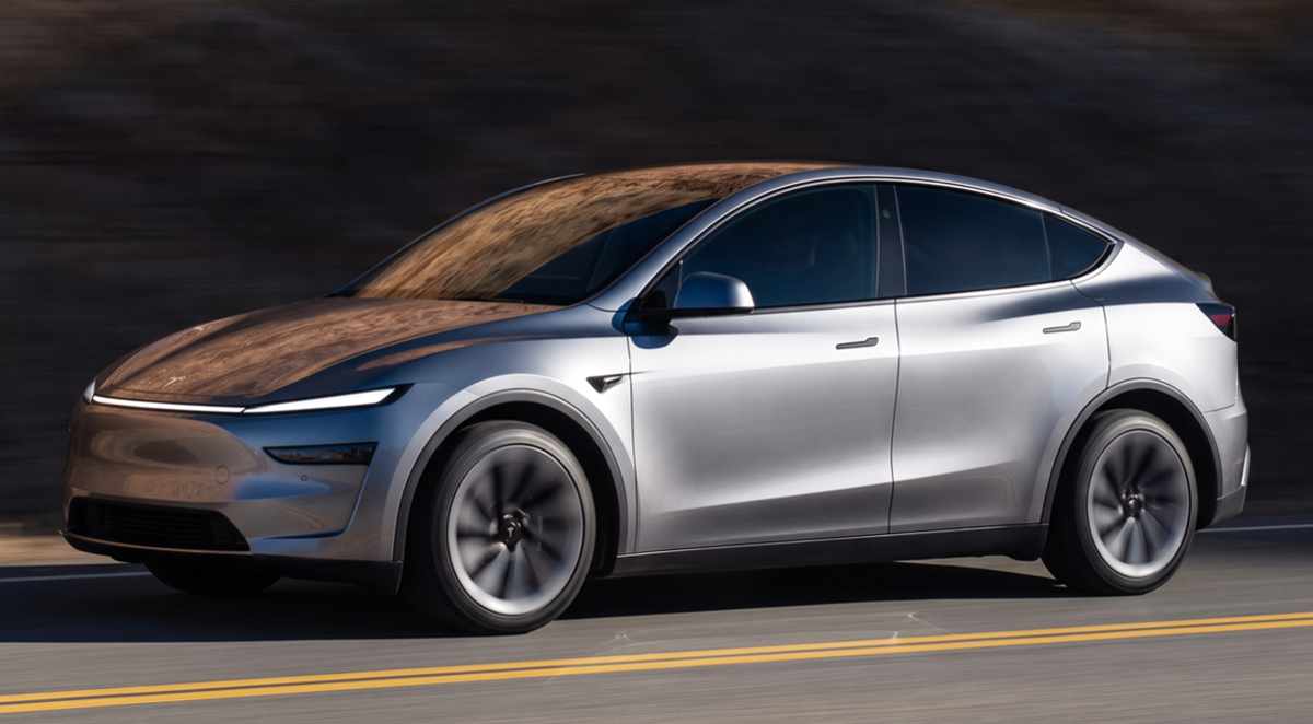 Crossover eléctrico Tesla Model Y color plata en movimiento sobre una carretera con líneas amarillas durante el día en Colombia.