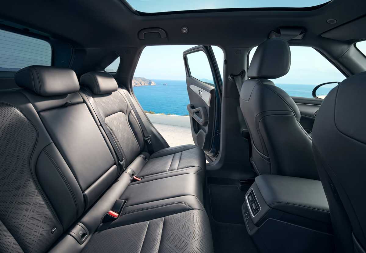 Vista panorámica del interior de la BYD Yuan Up DM-i GS desde el asiento trasero, mostrando el techo panorámico fijo, las salidas de aire traseras y los asientos tapizados en cuero sintético negro.