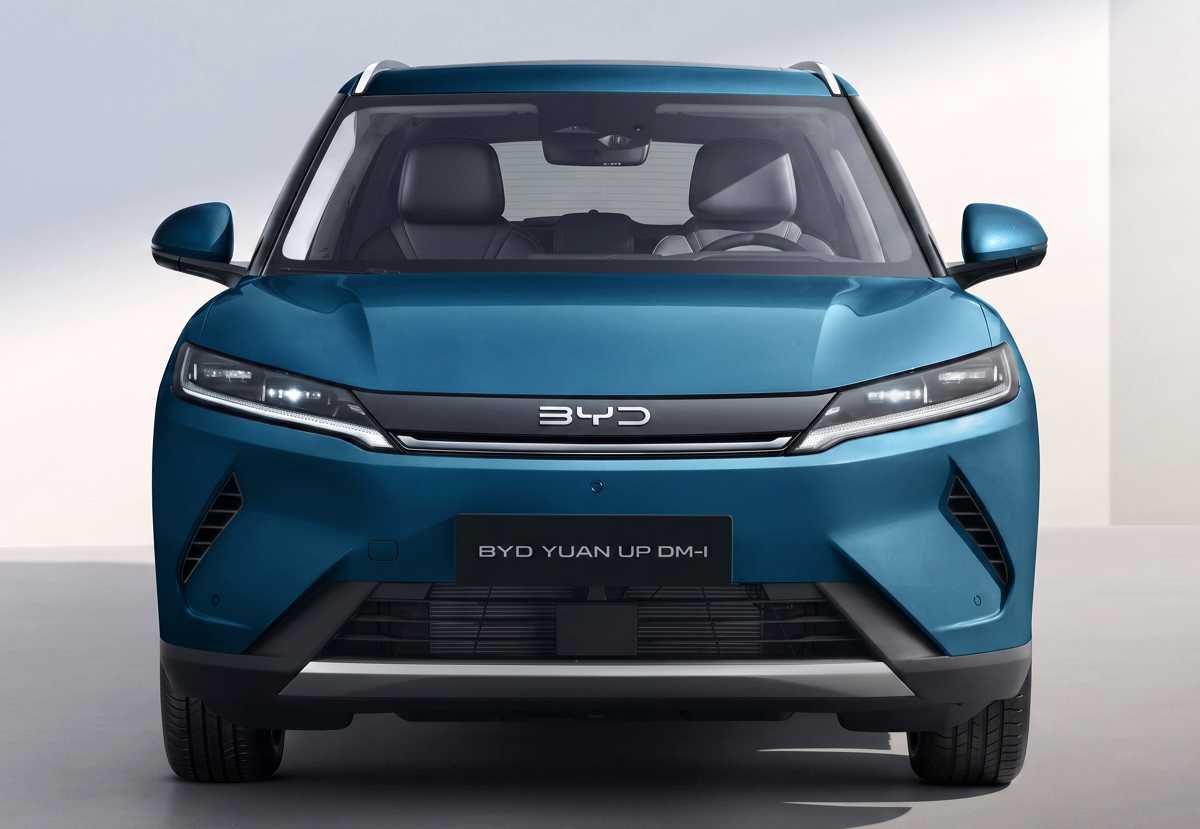 Vista frontal directa de la SUV híbrida enchufable BYD Yuan Up DM-i en color cian oscuro malaquita, destacando sus faros LED alargados, el emblema central de la marca y el diseño aerodinámico de la defensa inferior en un entorno de estudio.