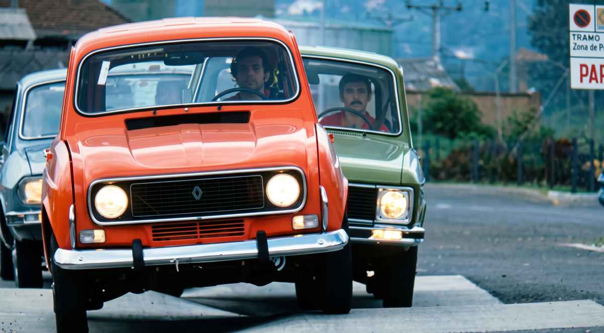 Tres clásicos Renault 4, 6 y 12 de colores naranja, verde y azul circulando en fila durante una prueba de ruta en Colombia.