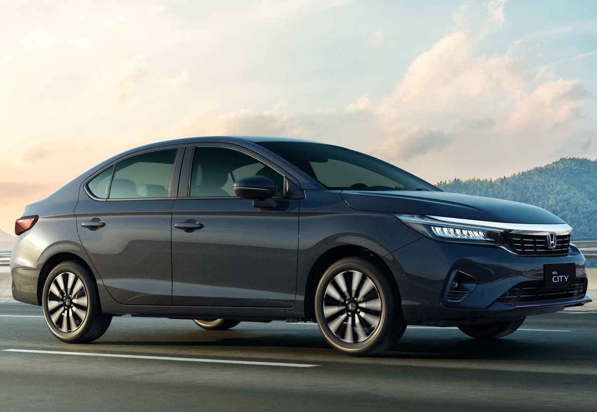 Automóvil sedán Honda City color gris oscuro rodando por una autopista con un paisaje montañoso al fondo.