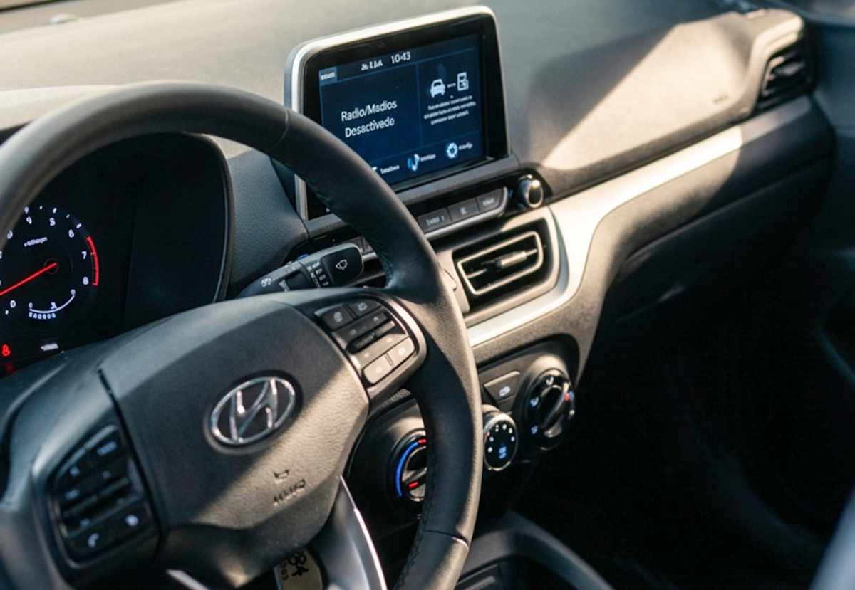 Detalle del diseño interior y puesto de conducción del Hyundai HB20, mostrando el volante multifunción, los controles manuales de aire acondicionado y la pantalla táctil multimedia de 8 pulgadas.