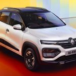 Vista de tres cuartos frontal del nuevo Renault Kwid 2027 color blanco, destacando su nueva parrilla y diseño exterior sobre un fondo naranja brillante.