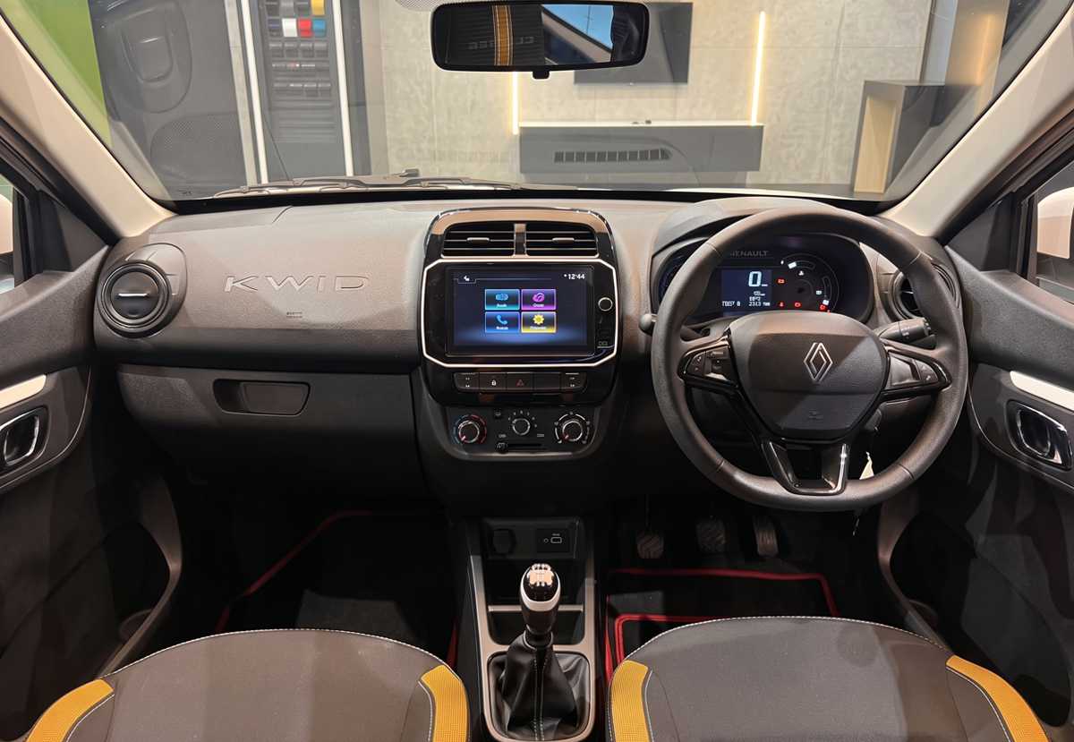 Interior del habitáculo del Renault Kwid 2027, equipado con el nuevo volante de tres radios, pantalla táctil central de 8 pulgadas y tapicería en color negro con detalles amarillos.