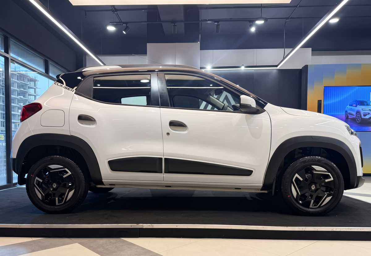 Vista lateral de perfil completo del Renault Kwid 2027 color blanco con techo negro exhibido en vitrina, destacando su altura al piso de 18,4 centímetros y silueta compacta.