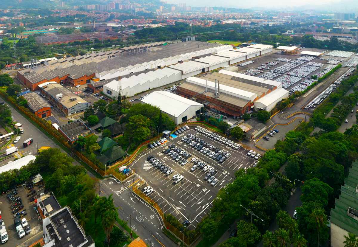 Fotografía aérea panorámica con dron de la fábrica de Renault-Sofasa en Envigado, mostrando las naves de ensamblaje y cientos de carros listos en el patio.