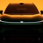 Vista frontal directa de la nueva SUV Changan Nevo Q06 en tono Verde Jade, destacando su firma de luz diurna continua LED encendida bajo un fondo cálido.