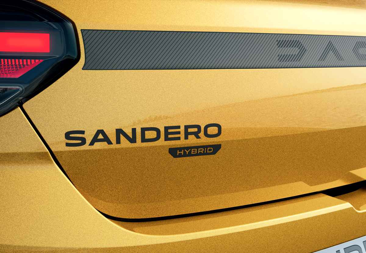 Detalle cercano del portón trasero del Dacia Sandero Stepway, donde resalta el nuevo emblema oscuro con la inscripción 'SANDERO HYBRID' sobre la pintura amarilla.