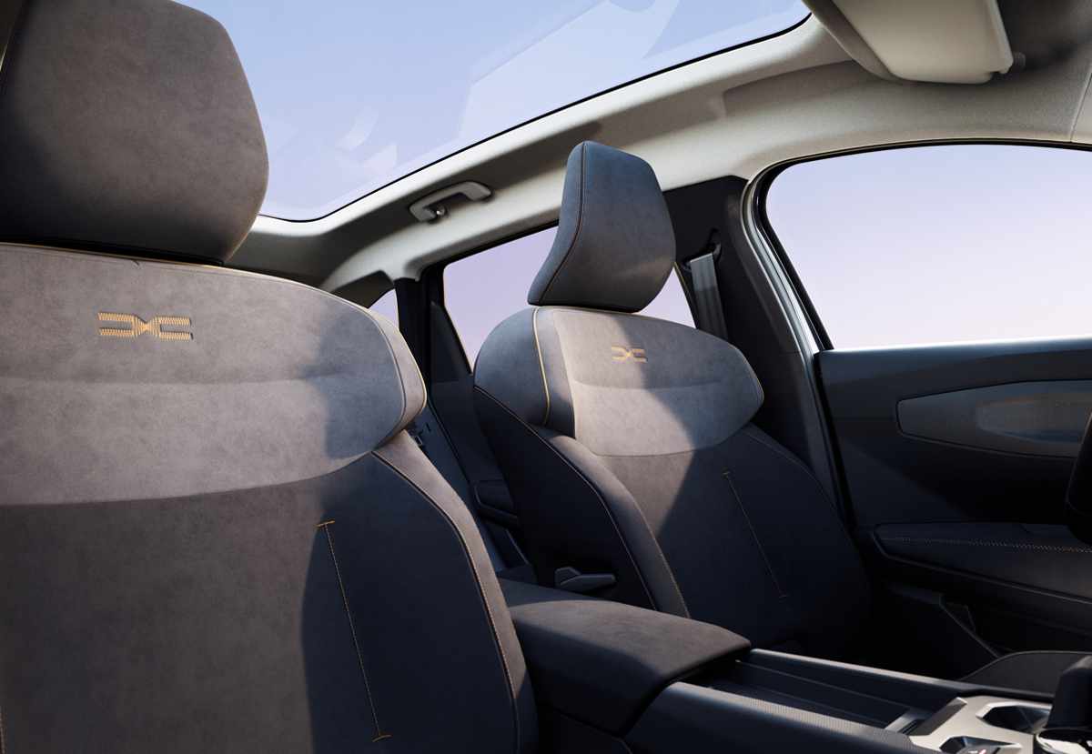 Asientos delanteros ergonómicos de la Dacia Striker tapizados en material textil, bajo la iluminación natural proporcionada por el amplio techo de cristal panorámico.