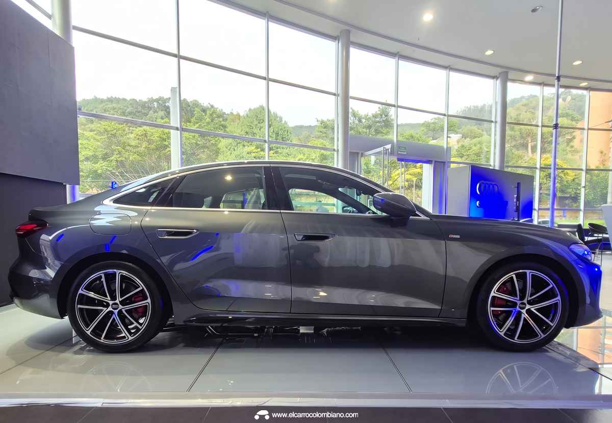 Perfil lateral completo del Audi A5 gris oscuro estacionado en vitrina, ilustrando su longitud de 4,83 metros, distancia entre ejes y silueta aerodinámica fluida.