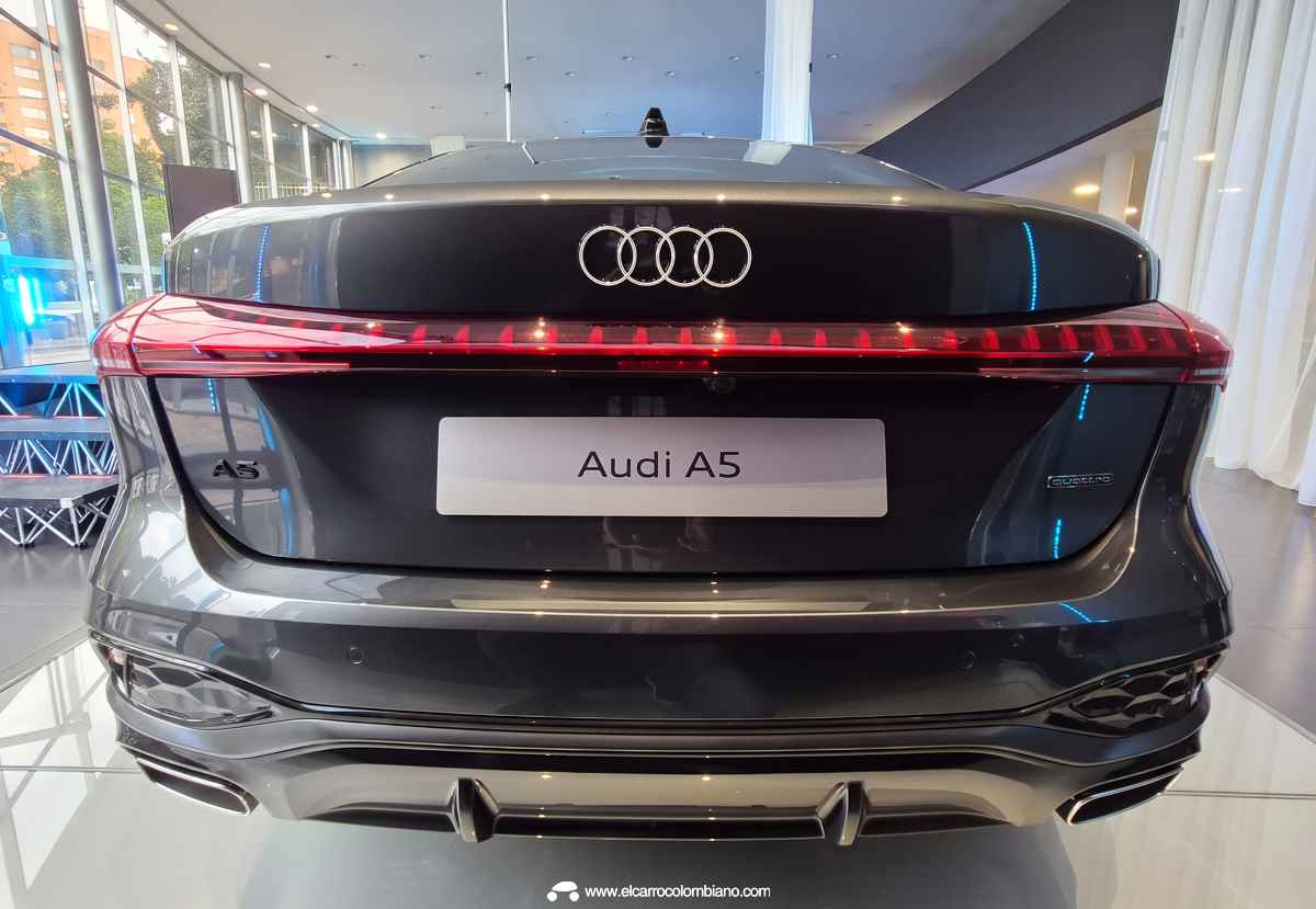 Plano trasero directo y simétrico del Audi A5, enfatizando el emblema central, la línea de luz roja continua, el portón eléctrico y la doble salida de escape funcional.