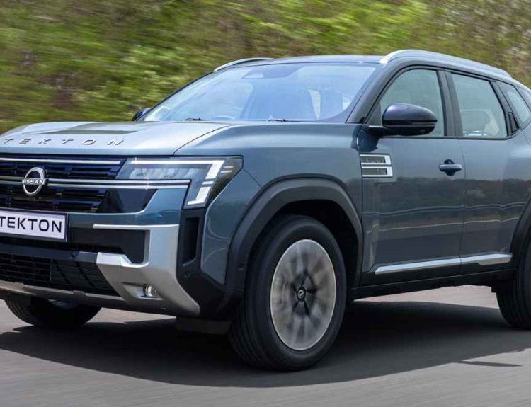 Vista frontal de tres cuartos de la nueva SUV Nissan Tekton color azul grisáceo en movimiento sobre una carretera, destacando su imponente parrilla frontal inspirada en la Nissan Patrol.