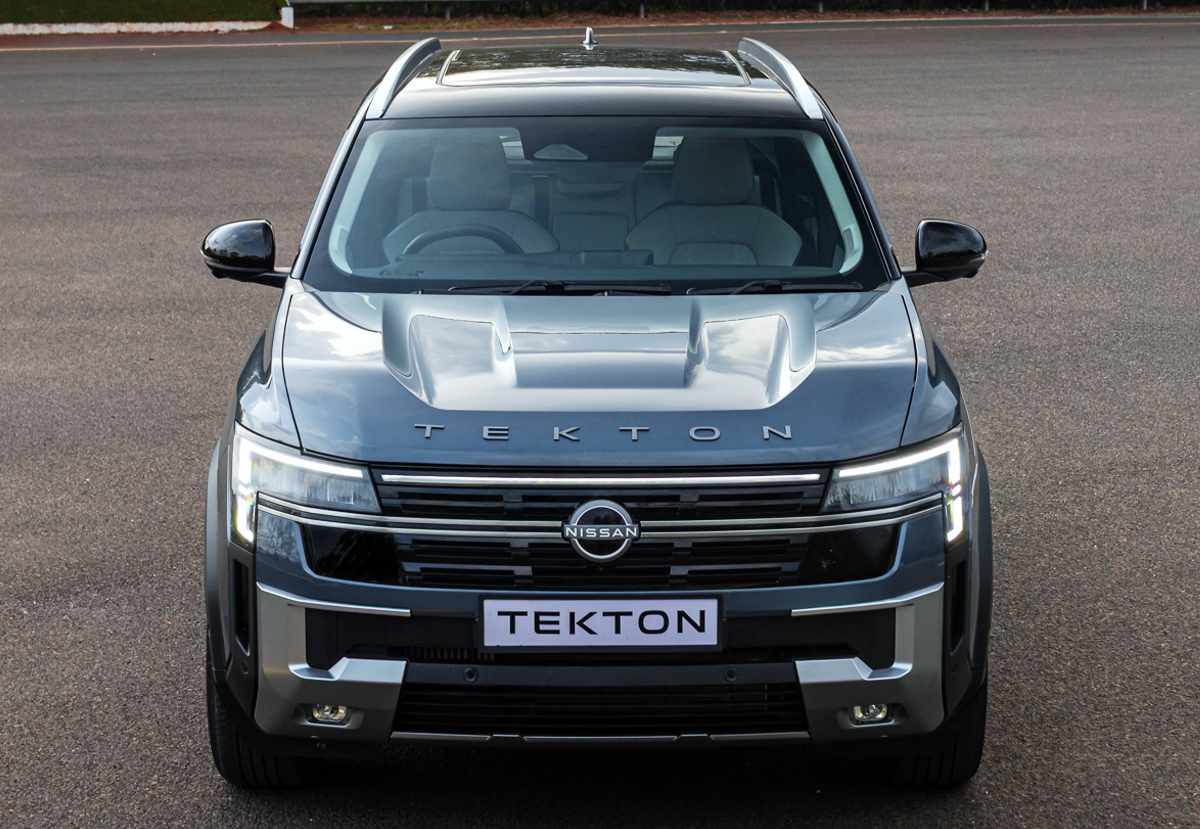 Toma frontal elevada directa de la nueva Nissan Tekton, resaltando las líneas de tensión sobre el capó con la tipografía de la marca y la amplia parrilla negra con acentos cromados horizontales.