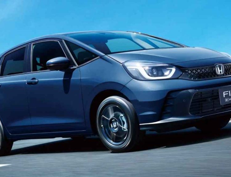 Vista frontal de tres cuartos del nuevo Honda Fit 2027 híbrido color azul oscuro en movimiento sobre una autopista, destacando su carrocería monovolumen y faros LED.