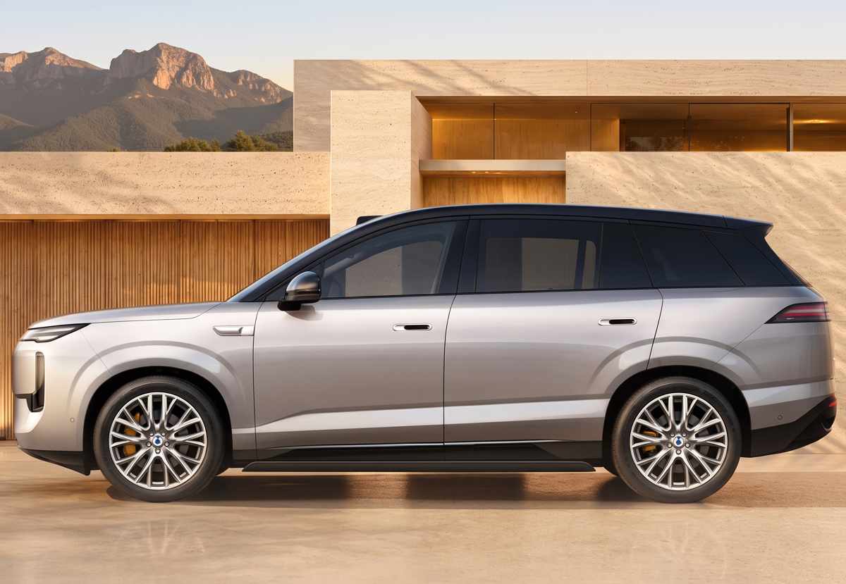 Perfil lateral completo de la SUV BYD Denza N8 frente a una casa moderna, ilustrando su extensa longitud de más de 5,15 metros diseñada para albergar cómodamente hasta tres filas de asientos.