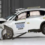 Momento exacto del impacto frontal con solapamiento de la nueva Mazda CX-5 blanca durante las exigentes pruebas de seguridad y choque del IIHS en laboratorio.