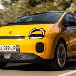 Vista frontal dinámica del nuevo Renault Twingo E-Tech eléctrico color amarillo circulando por una carretera, demostrando su agilidad durante las pruebas de manejo en Europa.
