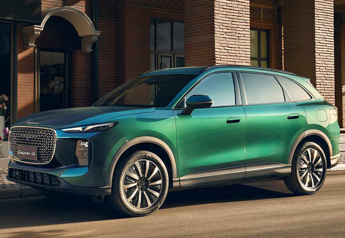 Perfil lateral elegante del SUV insignia Lepas L8 en tono verde esmeralda, estacionado frente a una fachada de ladrillo, mostrando su gran tamaño y rines de lujo.