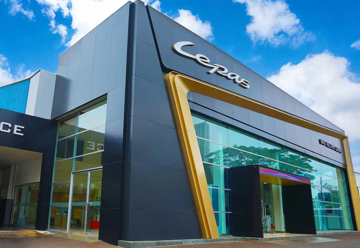 Fachada exterior de un moderno concesionario de la marca Lepas, con amplios ventanales de cristal, detalles arquitectónicos en dorado y el logotipo principal en la parte superior.